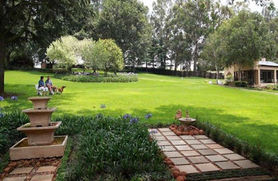 Eine Gruppe von Menschen sitzt in einem Garten neben einem Brunnen