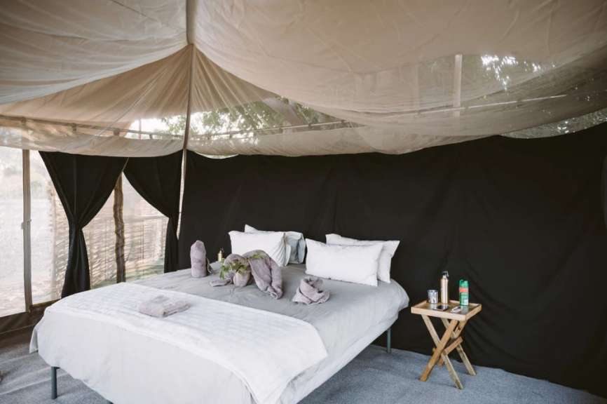 Ein Bett in einem Zelt mit schwarzen Vorhängen