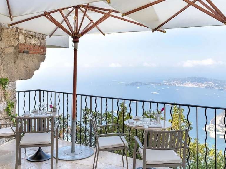 Ein Tisch und Stühle auf einem Balkon mit Blick auf das Meer