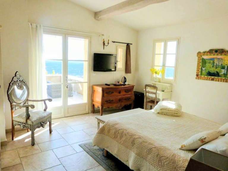 Ein Schlafzimmer mit einem Bett, einem Stuhl, einer Kommode und einem Fernseher