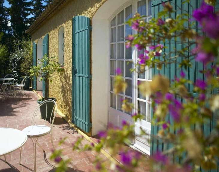 Eine Terrasse mit Tisch und Stühlen vor einem Haus mit blauen Fensterläden