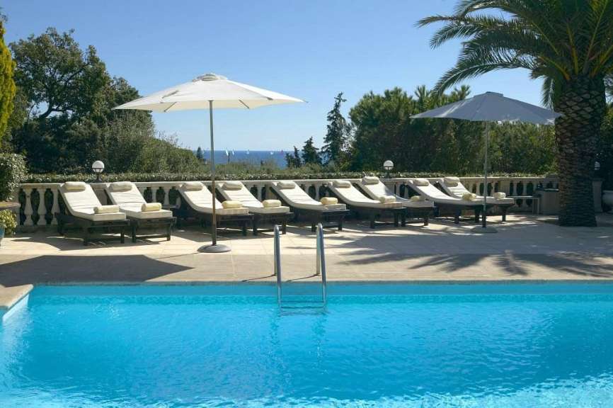 Ein Swimmingpool mit Liegestühlen und Sonnenschirmen umgeben