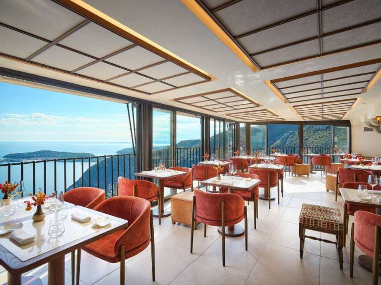 Ein Restaurant mit vielen Tischen und Stühlen mit Blick auf das Meer