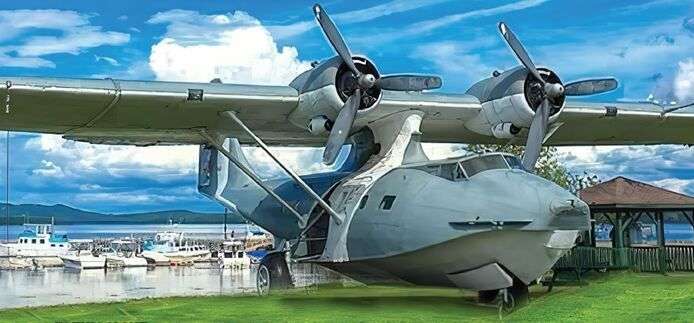 Ein großes Wasserflugzeug sitzt auf einer Wiese in der Nähe eines Sees .
