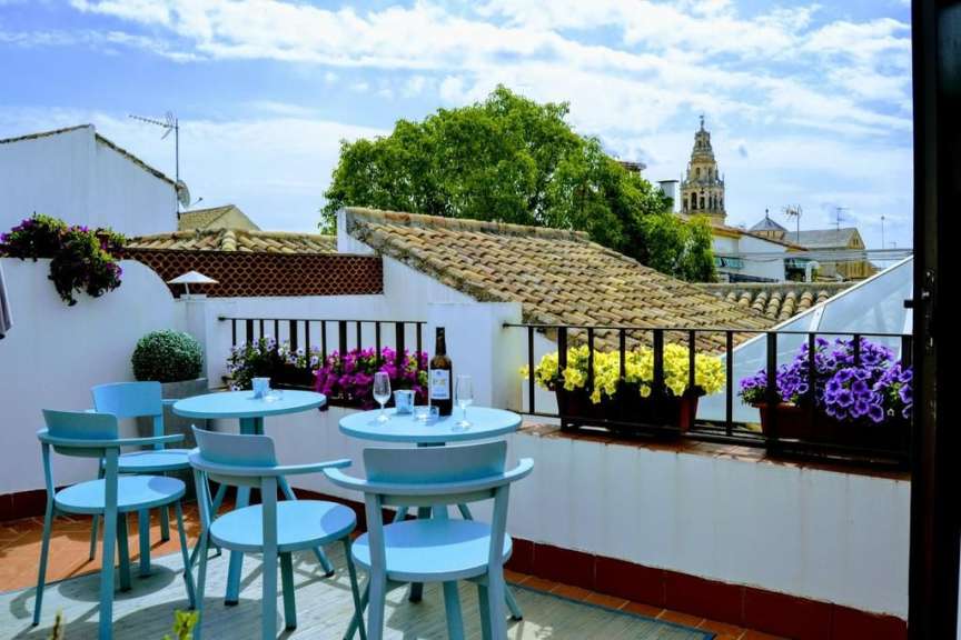 Ein Balkon mit blauen Stühlen und Tischen und einem Turm im Hintergrund