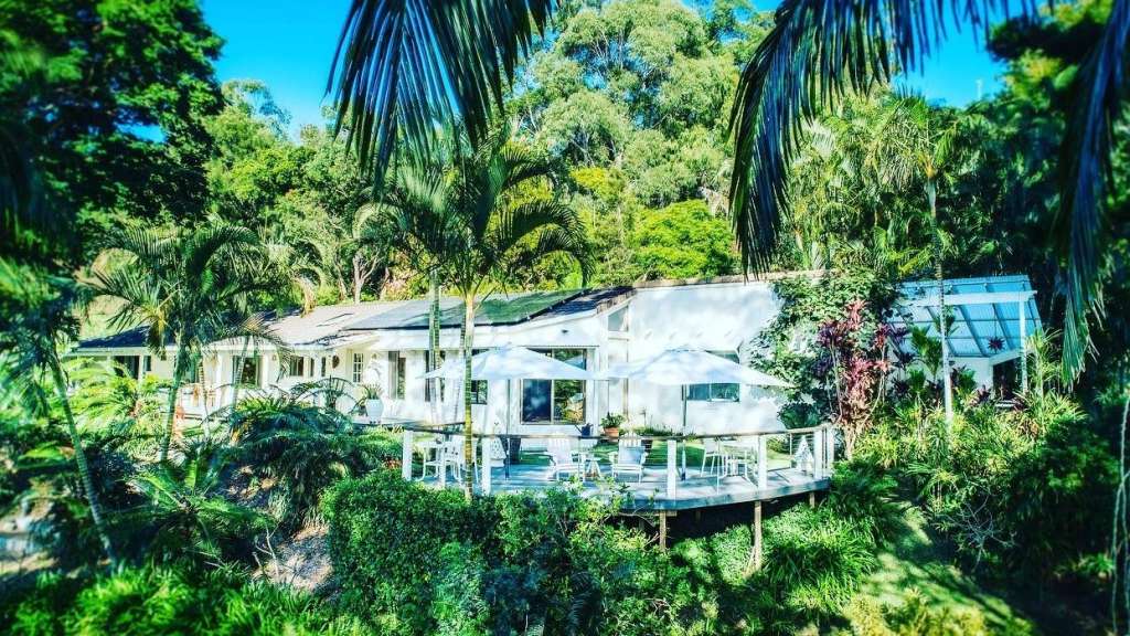 Ein weißes Haus umgeben von Palmen und Bäumen