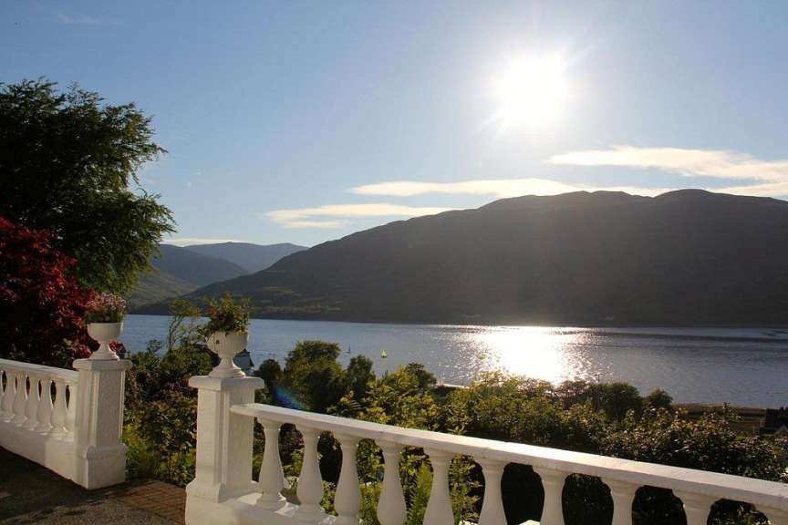 Ein Balkon mit Blick auf einen See mit Bergen im Hintergrund