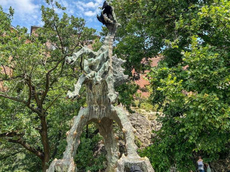 Eine Statue eines Drachen steht inmitten von Bäumen