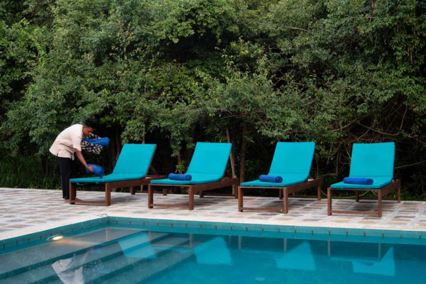 Eine Frau wäscht Liegestühle neben einem Swimmingpool