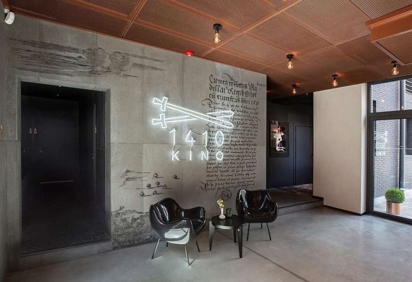 Ein Wohnzimmer mit schwarzen Stühlen und einem Leuchtreklame für das 140 kino