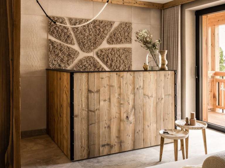 Auf dem Bild ist ein Tresen aus naturbelassenem Holz mit einem Moosrelief an der Wand hinter ihm zu sehen.