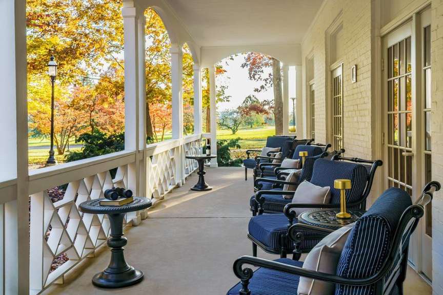 Eine Veranda mit vielen Stühlen und einem Tisch