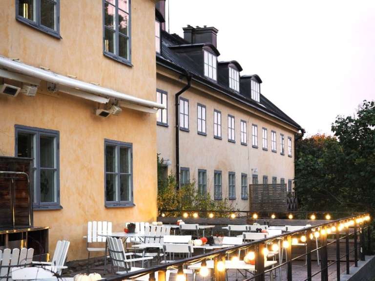 Ein Gebäude mit vielen Fenstern und einer Terrasse mit Tischen und Stühlen