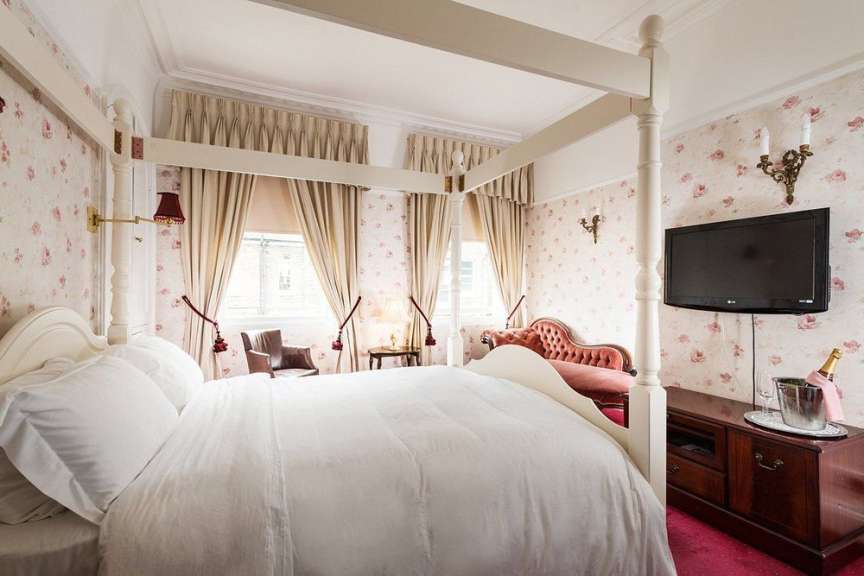 Ein romantisch eingerichtetes Zimmer mit einem Himmelbett und einem roten Sofa.