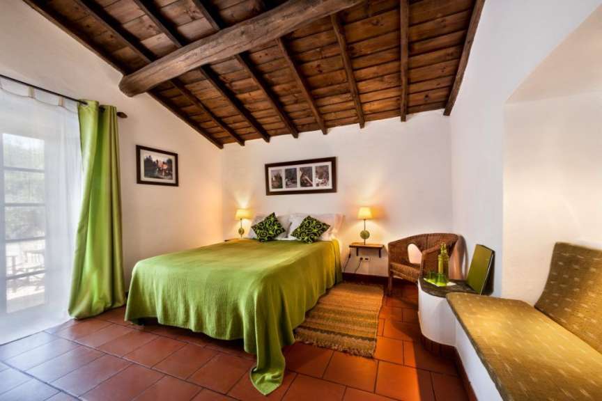 Ein gemütliches Schlafzimmer mit einem rustikalen Holzbalken-Decken und terracottafarbenen Fliesenböden.