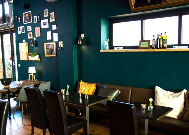 Eine Reihe von Tischen und Stühlen in einem Restaurant mit grünen Wänden