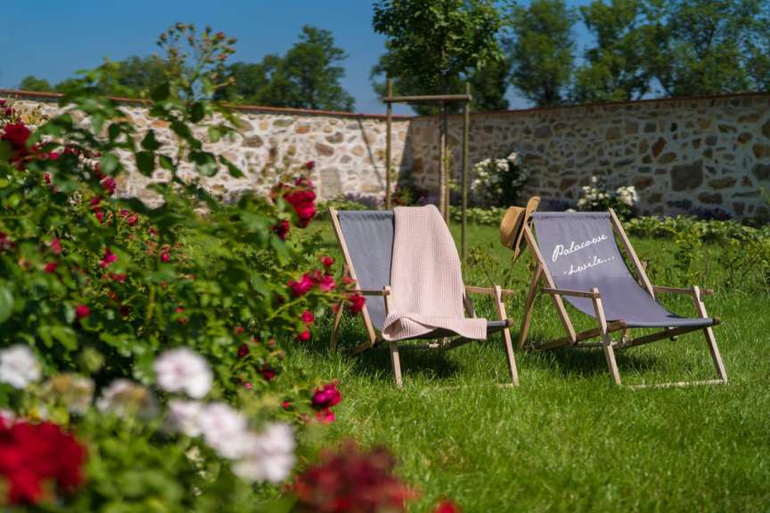 Zwei Liegestühle mit einer Decke darauf stehen in einem Garten