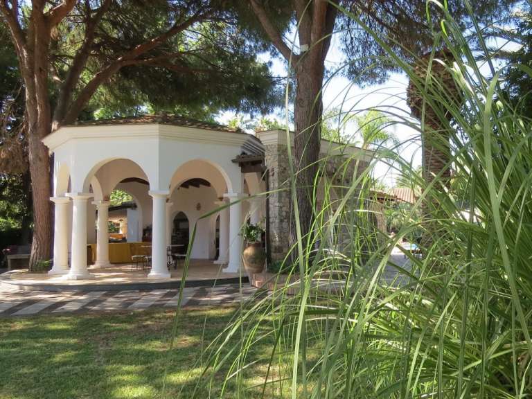 Ein weißer Pavillon mit weißen Säulen und Bäumen im Hintergrund