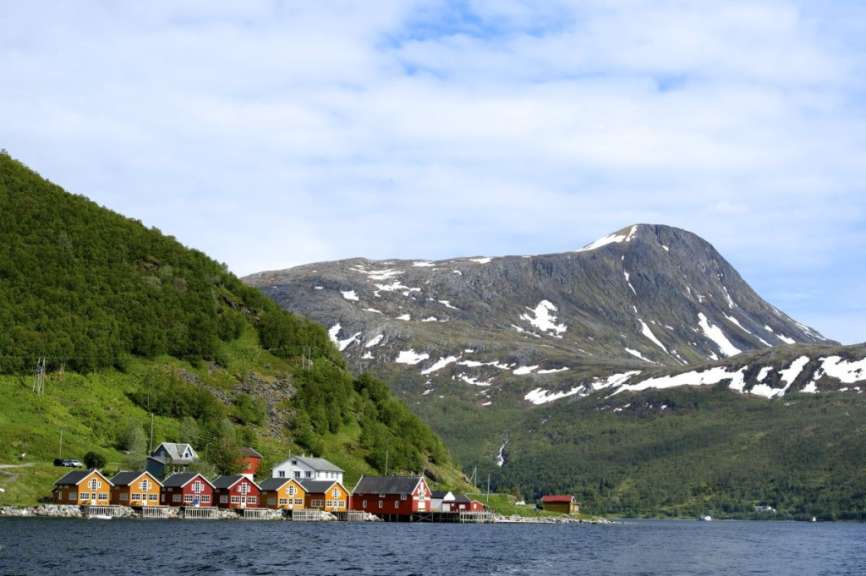 Eine Reihe von bunten Häusern an einem See mit einem schneebedeckten Berg im Hintergrund