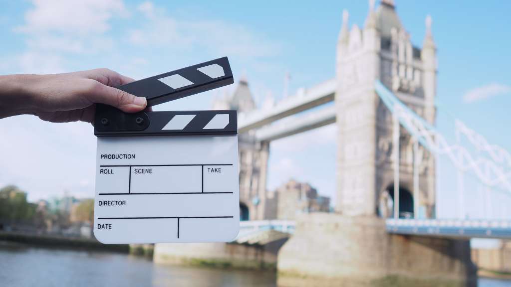 Eine Person hält einen Filmklappe vor einer Brücke