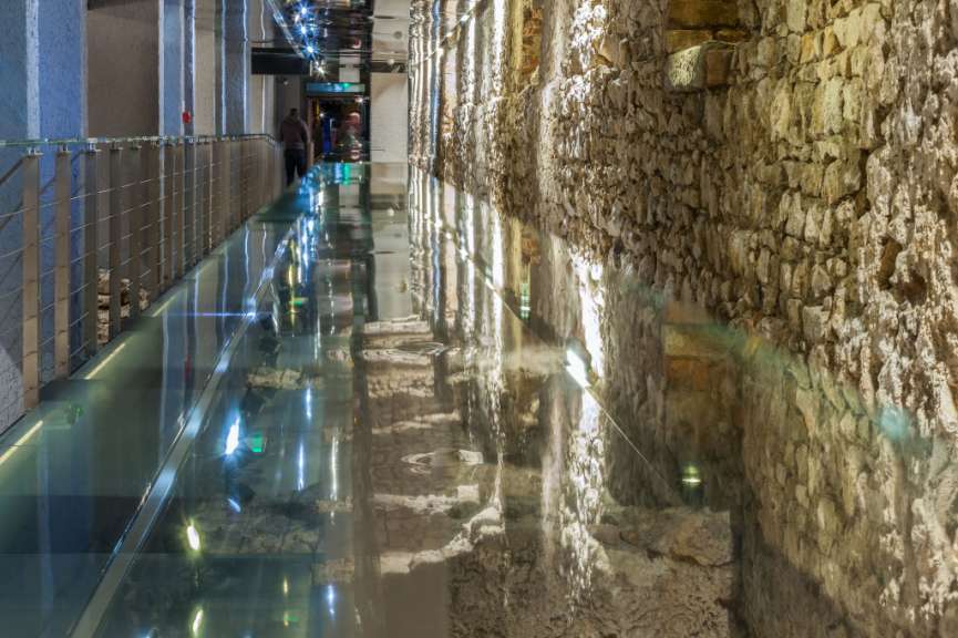 Menschen gehen durch einen Tunnel mit Steinwänden