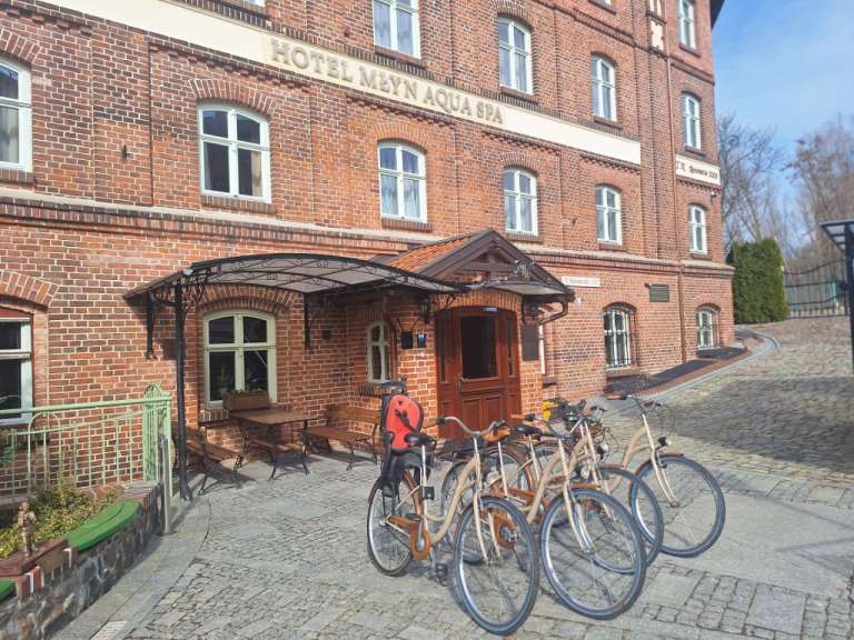 Eine Reihe von Fahrrädern vor einem Backsteingebäude mit der Aufschrift Hotel mayn aqua spa