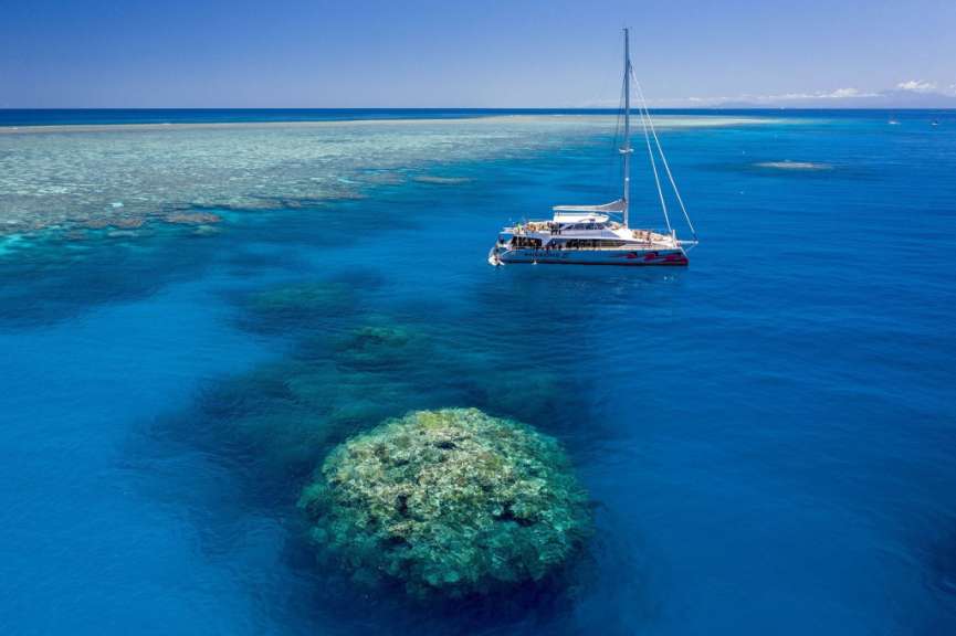 Ein Segelboot schwimmt im Ozean neben einem Korallenriff