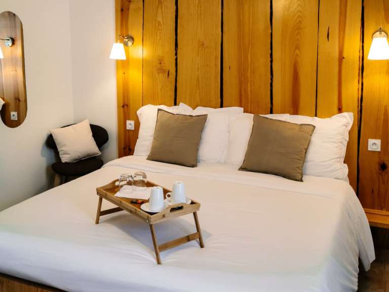Ein Bett mit einem Holztablett mit Tassen und Gläsern darauf