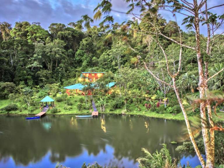 Ein kleines Boot schwimmt in einem See in der Nähe eines Hauses im Dschungel