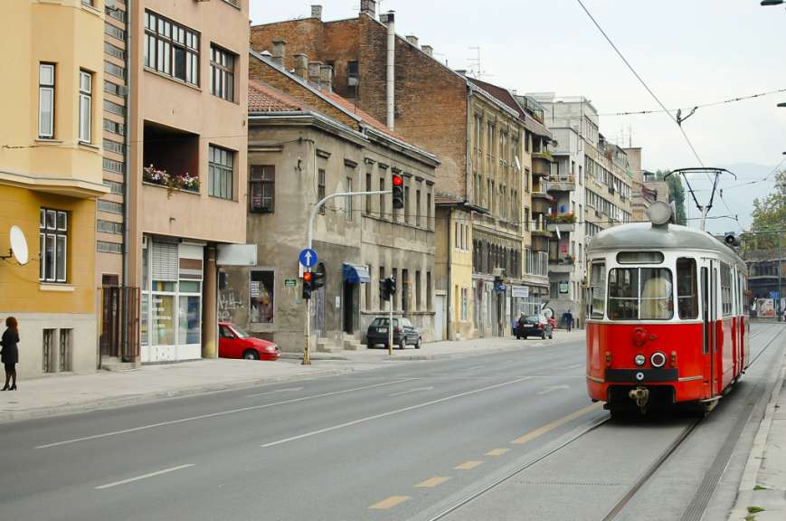 Eine rote Straßenbahn fährt auf einer Stadtstraße