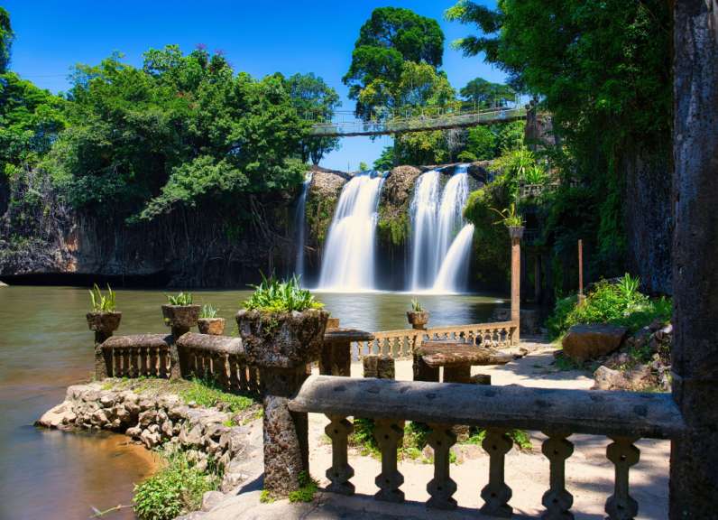 Ein Wasserfall mit einer Hängebrücke im Hintergrund