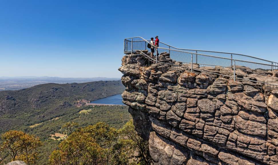 Menschen stehen auf einer Klippe mit Blick auf einen See