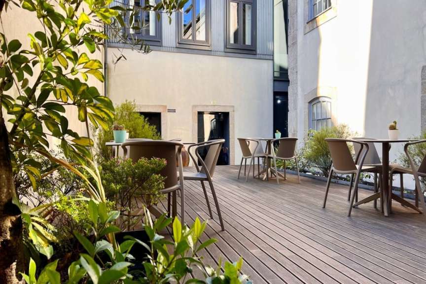 Tische und Stühle auf einem Holzdeck vor einem Gebäude