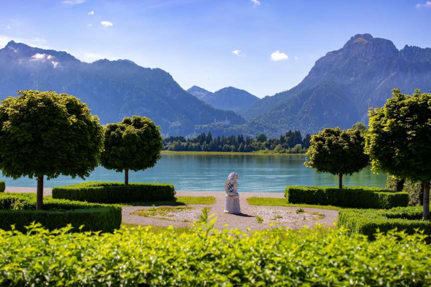 Eine Statue steht vor einem See mit Bergen im Hintergrund