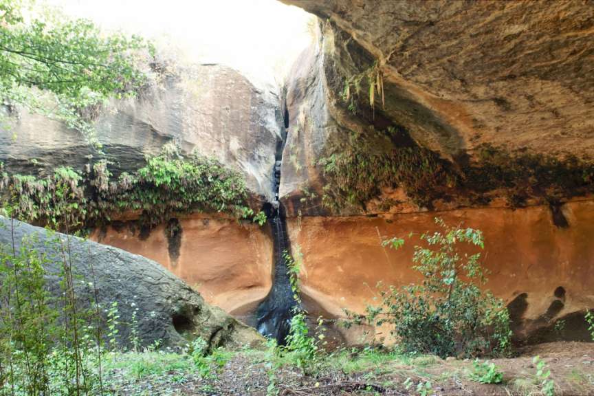 Ein Wasserfall stürzt aus einer Felswand in eine Höhle