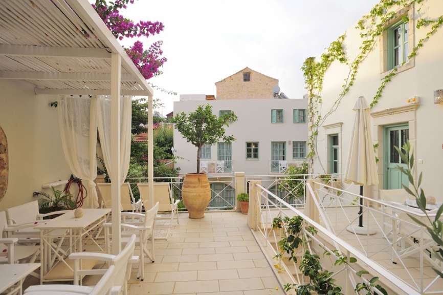 Ein Balkon mit einem Tisch und Stühlen und einer Vase mit einem Baum darauf