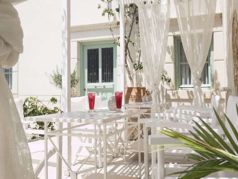 Ein Tisch und Stühle auf einer Terrasse mit weißen Vorhängen