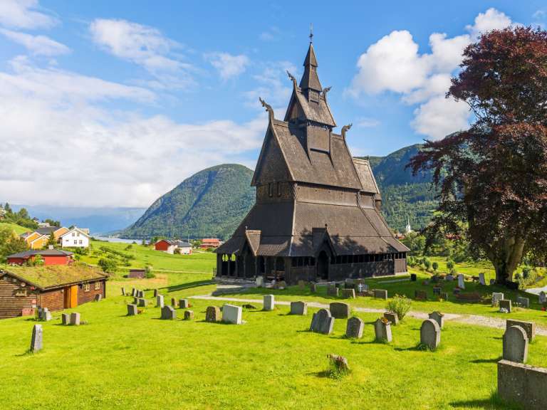 Eine sehr alte Holzkirche mit einem Friedhof davor