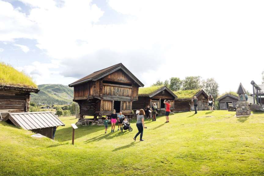 Eine Gruppe von Menschen steht vor einem Holzhaus mit grünem Dach