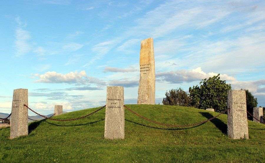 Eine Gruppe von Steinsäulen auf einer Wiese mit einem Obelisk darauf
