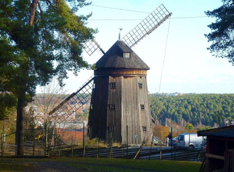 Eine hölzerne Windmühle mit einem weißen Lieferwagen davor