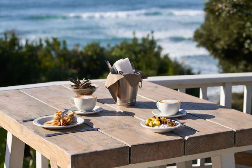 Ein Holztisch mit zwei Tassen Kaffee und zwei Tellern mit Essen darauf