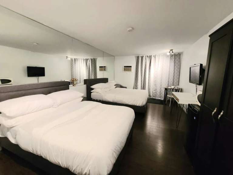 Ein Hotelzimmer mit zwei Betten, einem Schreibtisch und einem Kleiderschrank.