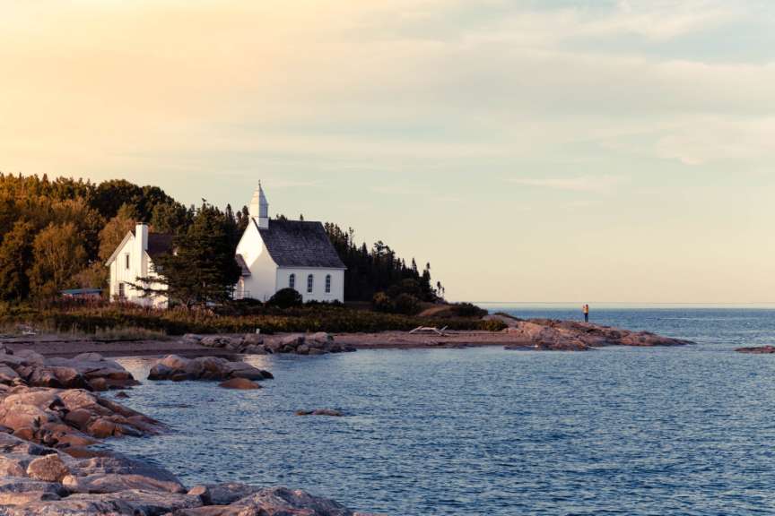 Eine kleine weiße Kirche sitzt an einem felsigen Strand