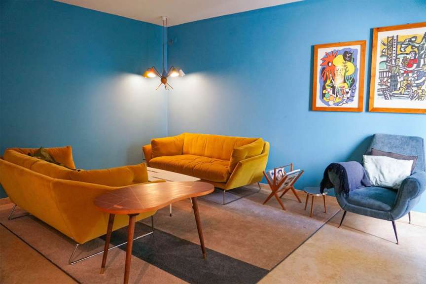 Ein Wohnzimmer mit blauen Wänden und gelben Möbeln