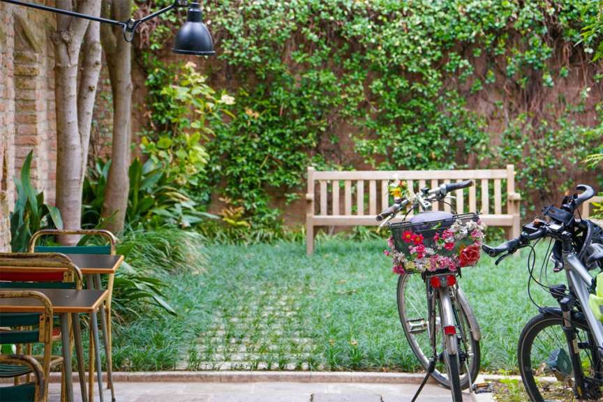 Ein Fahrrad mit einem Blumenkorb steht neben einem Tisch und Stühlen