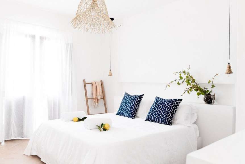 Ein weißes Schlafzimmer mit einem Bett und blauen Kissen