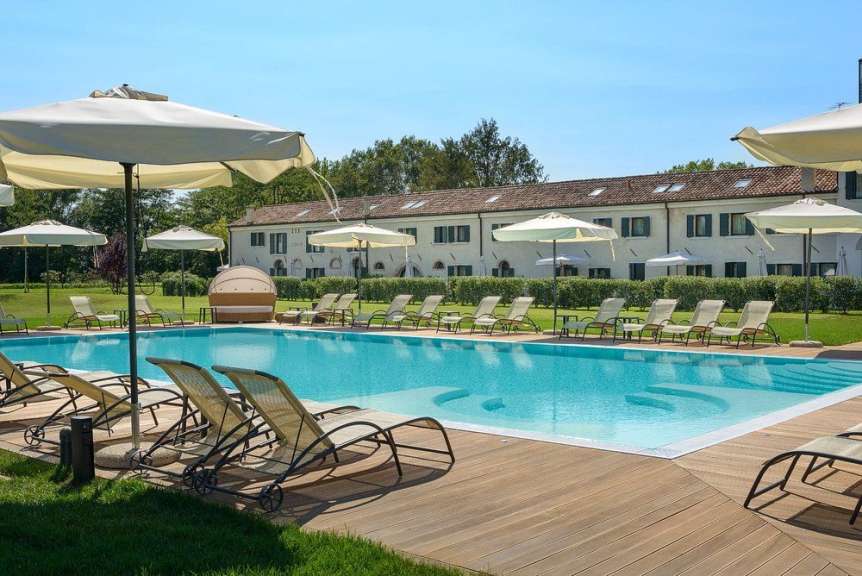 Liegestühle und Sonnenschirme umgeben einen großen Swimmingpool