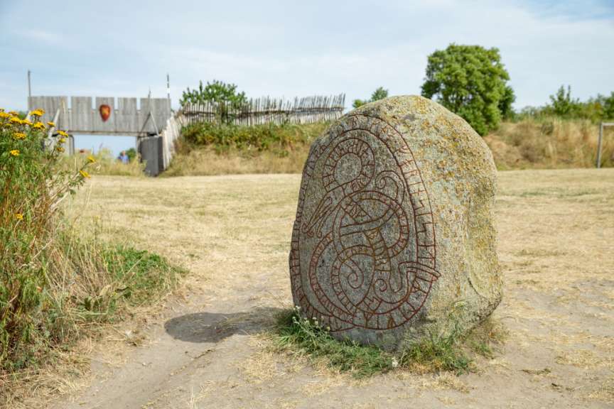 Ein großer Stein steht in einem Feld neben einem Holztor