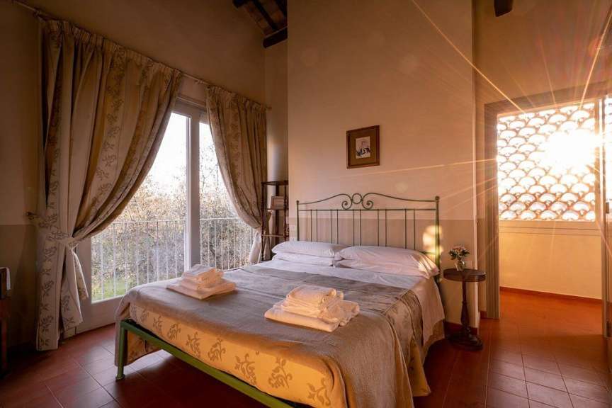 Ein sonnenbeschienenes Schlafzimmer mit einem Bett, das mit Handtüchern bedeckt ist, und einem großen Fenster mit Vorhängen.